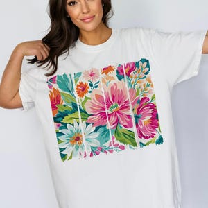 May include: White oversized t-shirt with a colorful floral print. The print features pink, red, orange, yellow, green, and blue flowers.