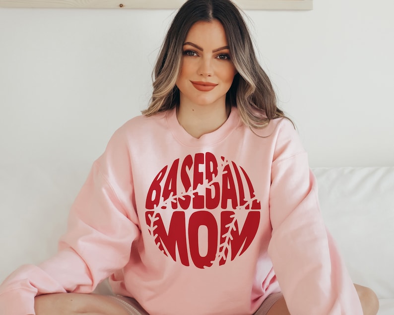 May include: A pink sweatshirt with a red baseball graphic that says "Baseball Mom".