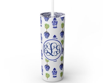 May include: A white stainless steel tumbler with a blue and white chinoiserie pattern and a green tree design. The tumbler has a monogram of the letters "LG" in a circle in the center.