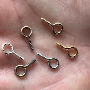 May include: Six screw-in eyelet hooks in various finishes, including silver, gold, and bronze.