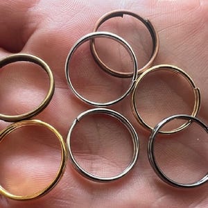 May include: Assortment of key rings in different sizes and finishes, including gold, silver, and bronze.
