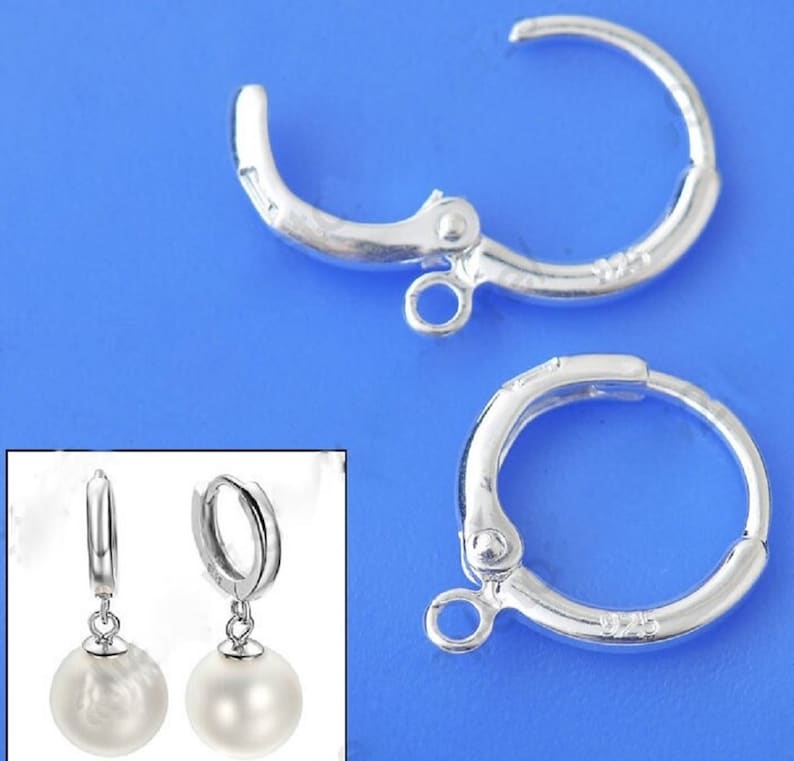 May include: Two silver-toned earring hoops with a hinged clasp. Each hoop has a small loop at the bottom for attaching a pendant. The hoops are shown with white pearl pendants attached.