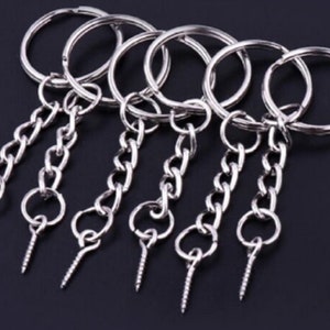 May include: Five silver keyrings with screw-on attachments and a chain link. Each keyring has a circular ring.