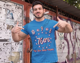 May include: A blue t-shirt with a white and red graphic of the Philadelphia 76ers logo with the text "10 9 8 76ers" and "Clap Your Hands Everybody".