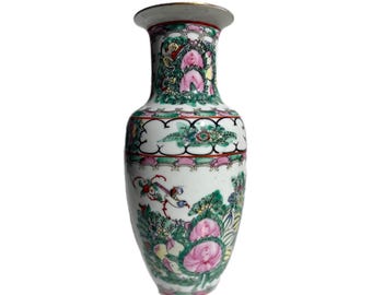May include: A decorative porcelain vase with a white base, featuring detailed hand-painted floral and bird designs in pink, green, and gold. The vase has a flared rim and a rounded body, showcasing an ornate aesthetic.