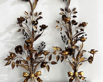 Peut inclure: Une paire d'appliques murales en métal doré avec un motif floral. Chaque applique présente un bouquet de roses, de feuilles et de tiges, avec un nœud en bas. Les appliques sont parfaites pour ajouter une touche d'élégance à n'importe quelle pièce.