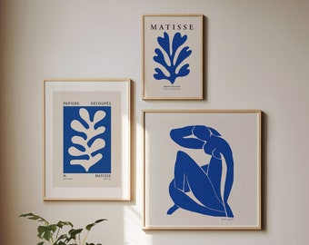 May include: Three framed art prints with a white background and blue designs. The top print features a blue stylized leaf with the text "MATISSE" above it. The middle print features a blue stylized leaf with the text "PAPIERS DECOUPES" above it and "MATISSE" below it. The bottom print features a blue stylized figure with the text "MATISSE" below it.