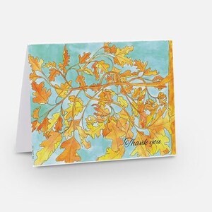 Pode incluir: Um cartão de agradecimento com uma ilustração em aquarela de um ramo de folhas de carvalho em tons de laranja e amarelo sobre um fundo azul claro. O texto "Obrigado" está escrito em itálico preto.
