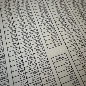 May include: A close-up of a printed color chart with numbered boxes. The chart includes color names like Blue, White, Purple, and Black, with corresponding numbers and codes for each color.