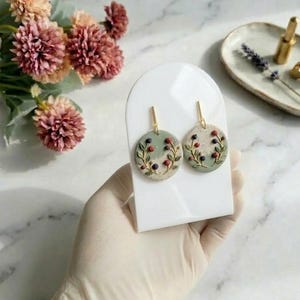 Op de afbeelding: Een set van drie keramische mokken met een gespikkelde, matte afwerking. De mokken zijn in de tinten crème, lichtgrijs en donkergrijs. Elke mok heeft een eenvoudig, modern ontwerp en een afgeronde handgreep.