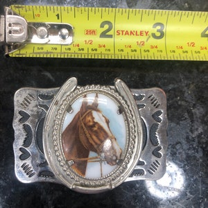 Belt buckle with raised stone horse picture on it