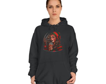 Puede incluir: Sudadera con capucha gris oscuro con un gráfico de una mujer con un diseño inspirado en Freddy Krueger. La obra de arte incluye una capucha a rayas rojas y verdes, un guante con garras y una taza de café. La sudadera con capucha es una prenda informal.