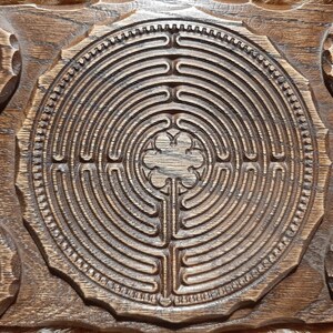 Pu&ograve; includere: Un vassoio di legno con un design a labirinto intagliato al centro. Il vassoio ha quattro portacandele ai bordi, ognuno con una candela rossa.