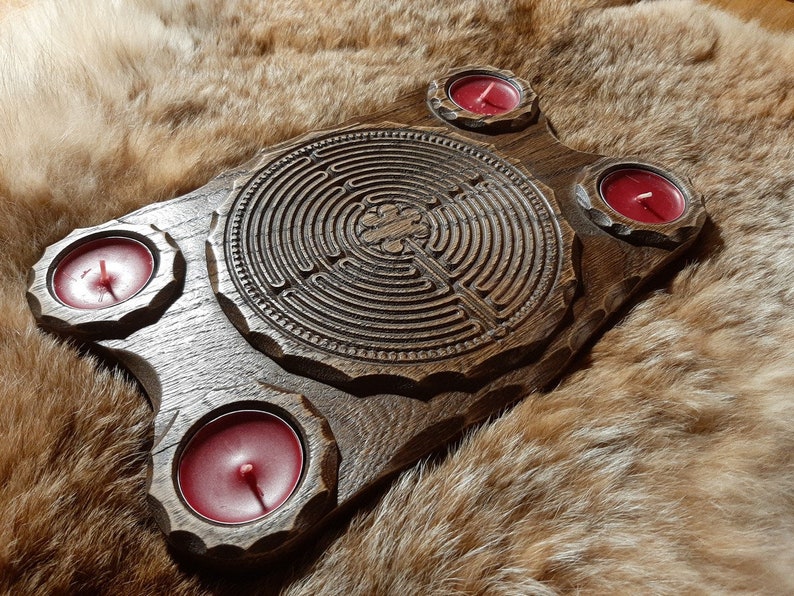 Pu&ograve; includere: Un vassoio di legno con un design a labirinto intagliato e quattro portacandele. I portacandele sono riempiti di candele rosse.