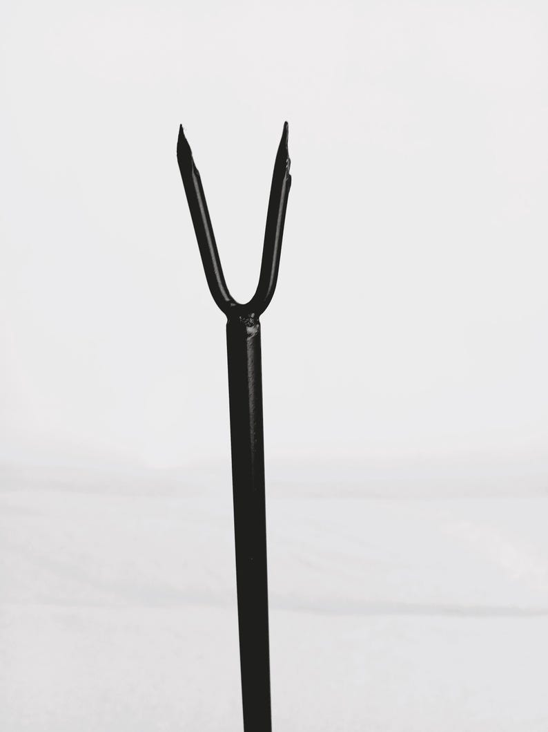 May include: Black metal stand with a forked top, designed to hold a small object.