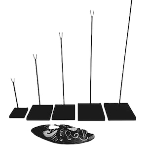 May include: Five black metal display stands with different heights, each with a square base and a forked top. A black and white mask with a decorative design is lying on the table below the stands.