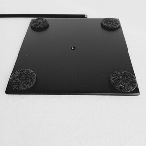 May include: Black metal stand with four black felt pads on the bottom. The stand has a round hole in the center.