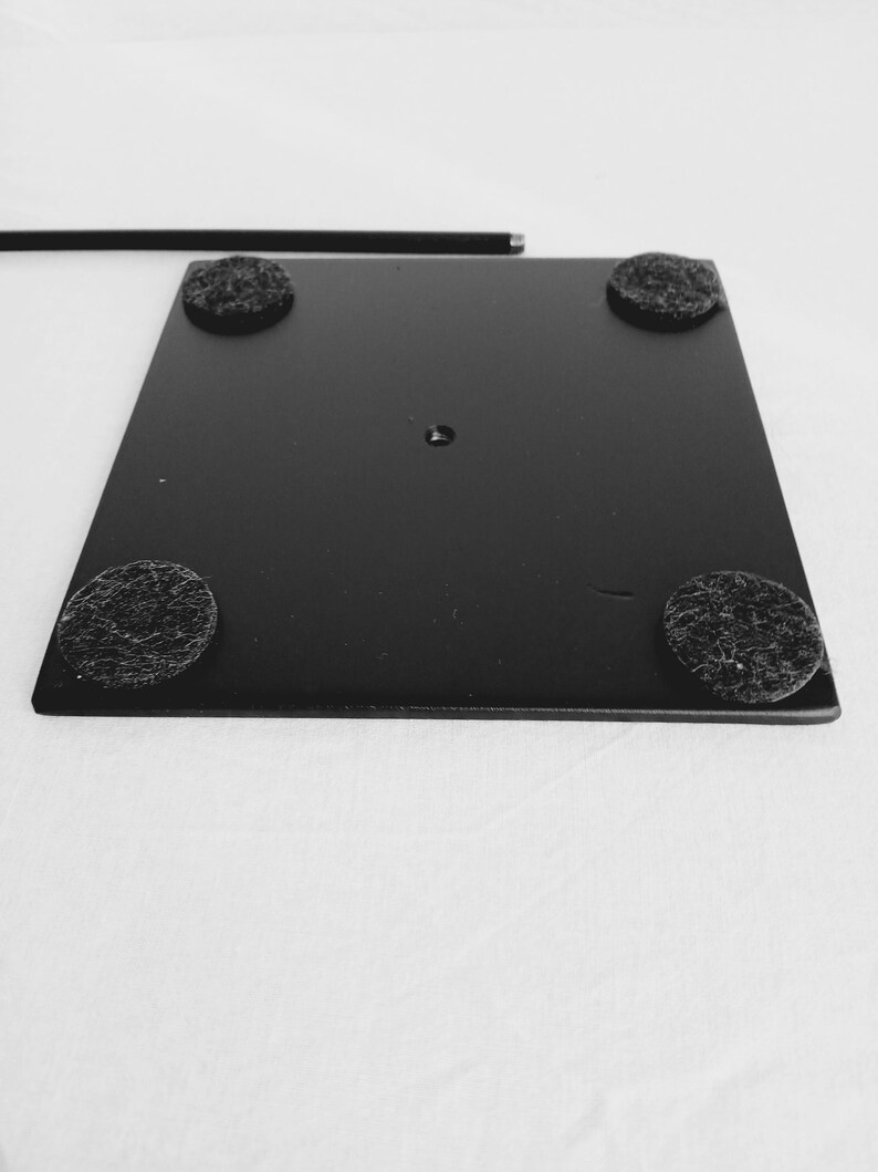 May include: Black metal stand with four black felt pads on the bottom. The stand has a round hole in the center.