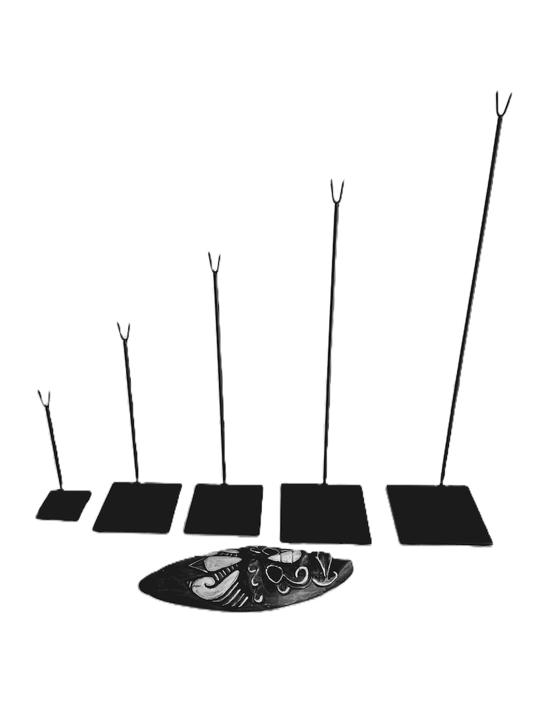 May include: Set of five black metal display stands with varying heights. Each stand has a square base and a single upright rod with a forked top.