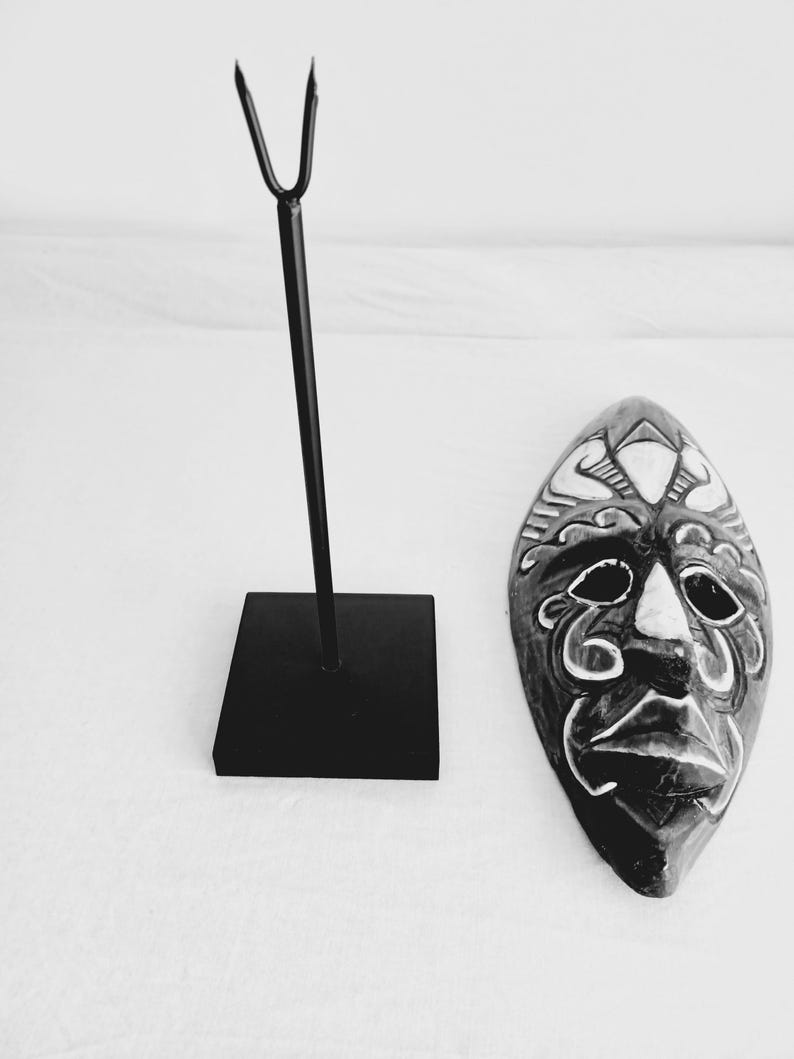 May include: Black and white wooden mask with intricate carvings and a stand. The mask has a human face with a wide mouth and large eyes.
