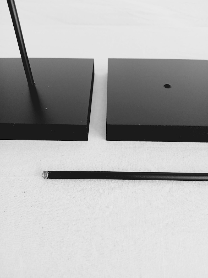 May include: Two black square bases with a black metal rod. The rod has a threaded end.