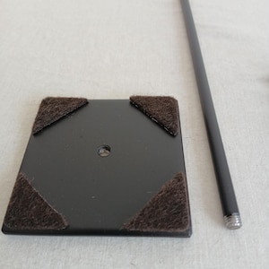 May include: Black metal display stand with a square base and four felt pads. The stand has a metal rod with a forked top.