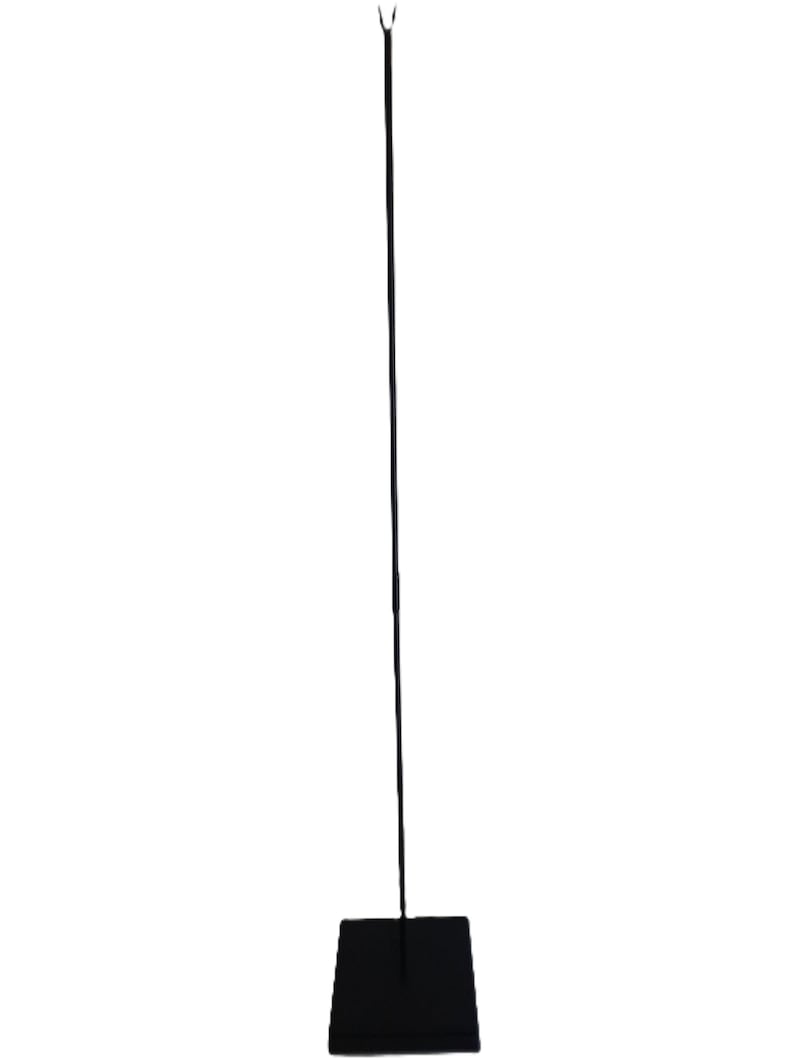 May include: Black metal stand with a square base and a long, thin rod extending upwards. The rod has a hook at the top.