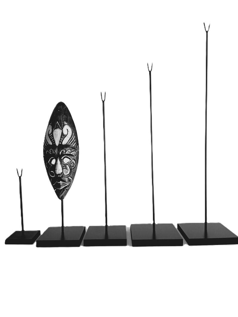 May include: Five black metal display stands with black bases. The stands are different heights and are used to display objects like masks.