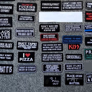 Pode incluir: Coleção de patches pretos bordados com texto branco. Apresentam frases como "Maximum Effort", "Black Lives Matter", "I Love Pizza" e "Prayer". Perfeitos para personalizar jaquetas ou bolsas com mensagens.