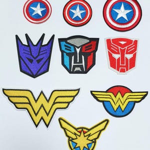 May include: Nine embroidered iron-on patches featuring various superhero and cartoon characters. The patches include Captain America, Optimus Prime, Megatron, and Wonder Woman.