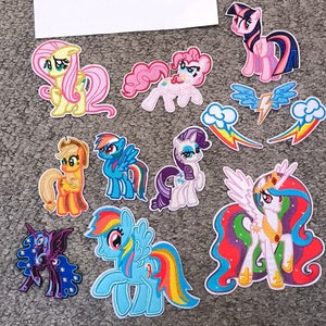 May include: A set of 10 embroidered iron-on patches featuring characters from the My Little Pony franchise. The patches include Twilight Sparkle, Rainbow Dash, Pinkie Pie, Fluttershy, Rarity, Applejack, Celestia, Luna, and two rainbow-themed patches.