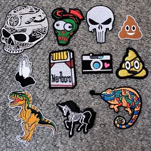 Puede incluir: Un conjunto de 12 parches para planchar con diferentes diseños, que incluyen una calavera, un personaje de dibujos animados, un emoji de caca, una cámara, un unicornio, un camaleón y una cajetilla de cigarrillos con la palabra "Marlboro" impresa.