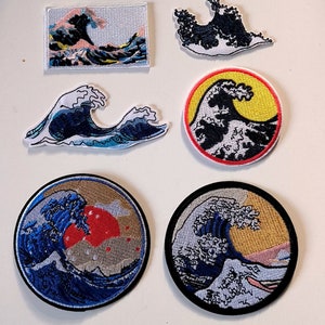 May include: Set of 6 embroidered iron-on patches featuring different interpretations of the Great Wave off Kanagawa, a famous Japanese woodblock print by Hokusai. The patches are in various colors, including blue, white, black, red, and yellow.