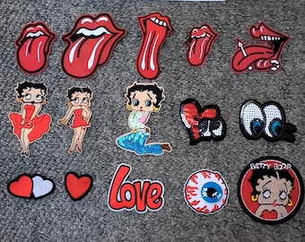 May include: Assortment of iron-on patches featuring cartoon characters, lips, eyes, and hearts.  The patches include Betty Boop, a red heart, a pair of eyes, and a red heart with a white center.