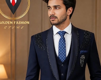 May include: A navy blue three-piece suit with a white dress shirt and a patterned blue tie. The suit features decorative embellishments on the lapels and a pocket square. The Golden Fashion Store logo is visible in the upper left corner.