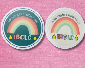 May include: Two circular stickers featuring a rainbow graphic, the text "Advocating for a healthy future" arched above, the acronym "IBCLC" in the centre, and two yellow water drop icons on either side. One sticker has a dark teal background.