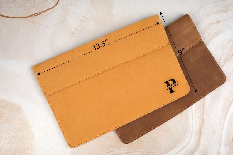 Pu&ograve; includere: Due custodie per laptop in pelle, una giallo senape e una marrone. La custodia gialla misura 34,3 cm di lunghezza e 22,9 cm di larghezza. La custodia gialla ha una chiusura a patta e una iniziale nera "P" con il nome "PORTER" sotto.
