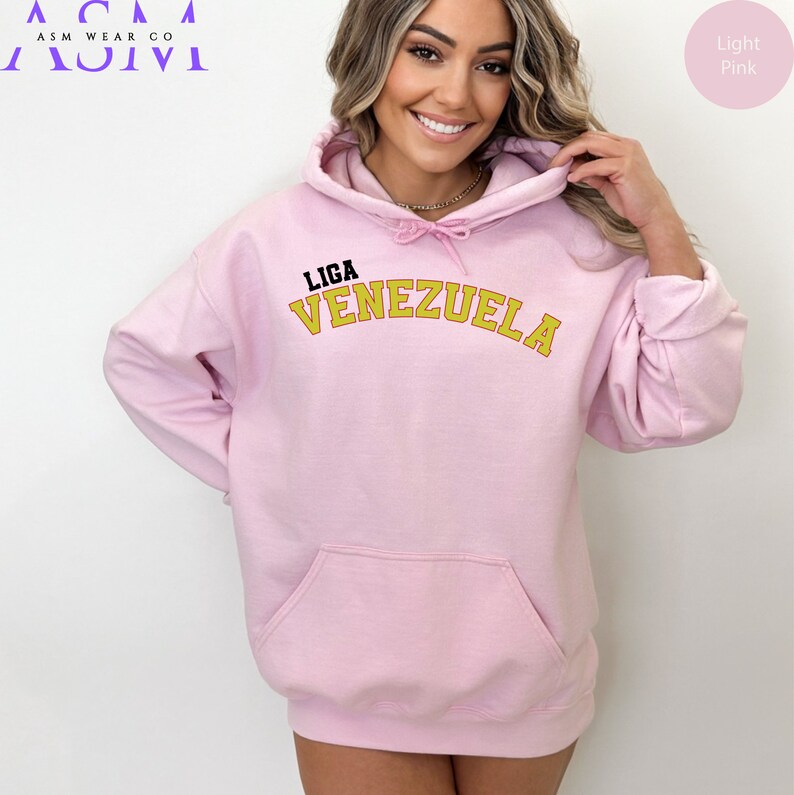 May include: A light pink hooded sweatshirt with the text "LIGA VENEZUELA" in a yellow arch across the front.