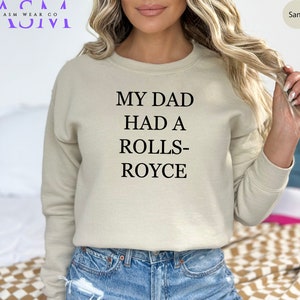 May include: A sand-colored sweatshirt with the text "My Dad Had A Rolls-Royce" printed on the front.
