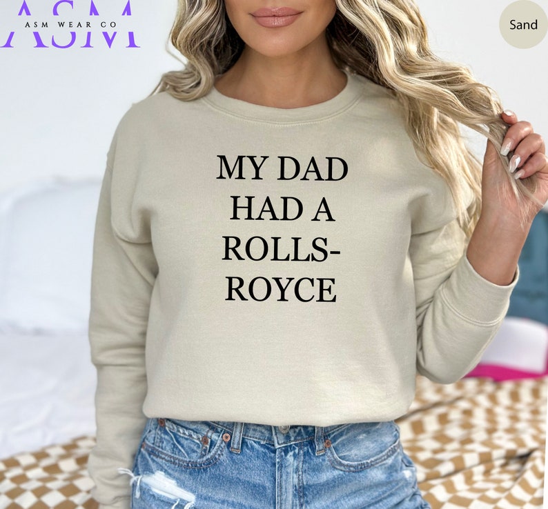 May include: A sand-colored sweatshirt with the text "My Dad Had A Rolls-Royce" printed on the front.