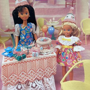 May include: Two dolls wearing party hats and dresses are featured in a scene with a table set for a party. The table is covered with a decorative cloth and presents. The text "Surprise Party" is displayed above the dolls.