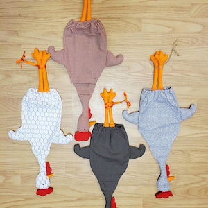 Puede incluir: Cuatro bolsas de almacenamiento de tela con forma de gallina, patas naranjas y crestas rojas. Las bolsas presentan varios estampados, incluyendo un dise&ntilde;o de panal blanco, cuadros vichy rojos y blancos, lunares negros y chevron gris.