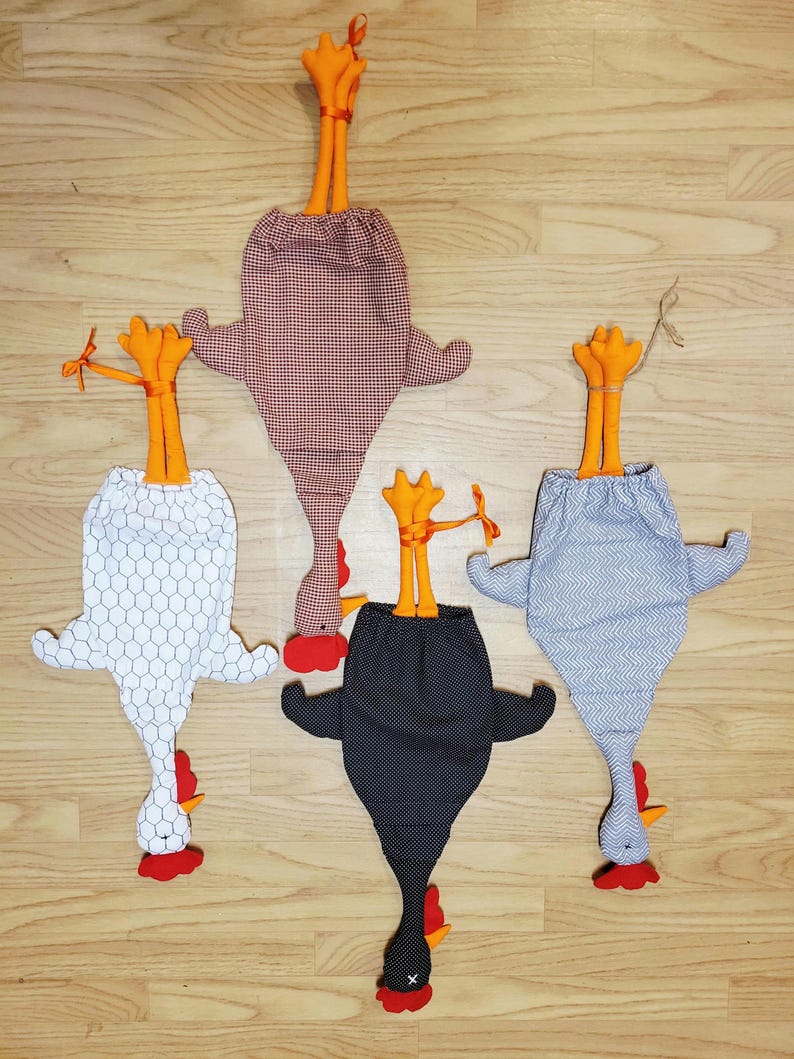 Puede incluir: Cuatro bolsas de almacenamiento de tela con forma de gallina, patas naranjas y crestas rojas. Las bolsas presentan varios estampados, incluyendo un dise&ntilde;o de panal blanco, cuadros vichy rojos y blancos, lunares negros y chevron gris.