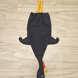 Puede incluir: Una bolsa de tela con forma de gallina sobre un fondo negro con lunares blancos. El dise&ntilde;o incluye patas amarillas atadas con una cinta color crema en la parte superior, una cresta y barbillas rojas, y un pico amarillo. El cuerpo tiene dos alas laterales.