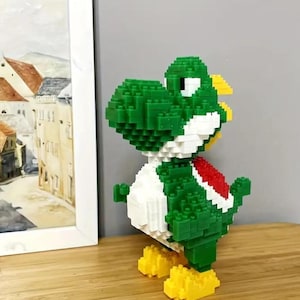 May include: A green and white Yoshi character made of small plastic blocks. The character has a red saddle and yellow feet.