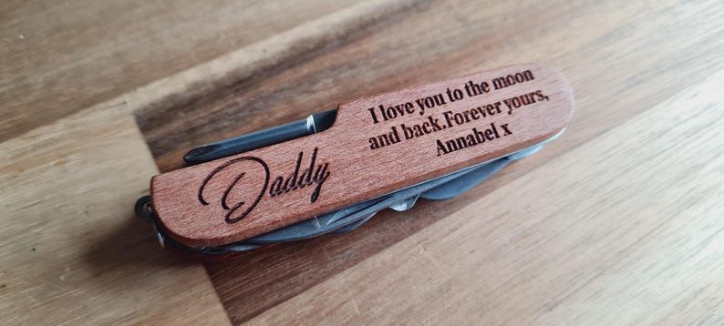 May include: A wooden multi-tool with a stainless steel blade and tools. The tool is engraved with the word "Daddy" and the message "I love you to the moon and back. Forever yours, Annabel x."
