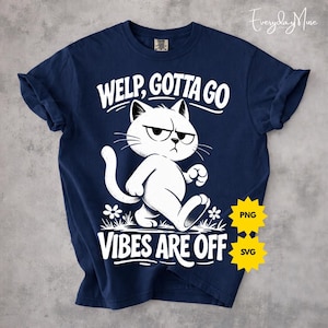 Puede incluir: Camiseta azul marino con una ilustración blanca de un gato gruñón caminando. El texto "WELP, GOTTA GO" y "VIBES ARE OFF" están impresos encima y debajo del gato. Las mangas están dobladas.