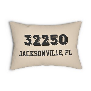 May include: A rectangular beige cushion displaying the black text "32250" above "JACKSONVILLE, FL". The cushion is a light tan colour and has a soft appearance. The text is in a bold, sans-serif font.