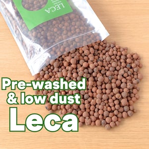 May include: A bag of pre-washed and low dust Leca growing medium. The Leca is a light brown colour and is spilling out of the bag onto a wooden surface. The bag has a green label with the word "LECA" printed on it.