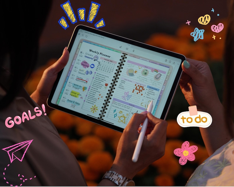 May include: A person holding a tablet displaying a weekly planner with colorful graphics and text. The planner includes sections for grocery shopping, goals, and to-do lists. The word "GOALS!" is written in pink, and a pink paper airplane is drawn on the image.